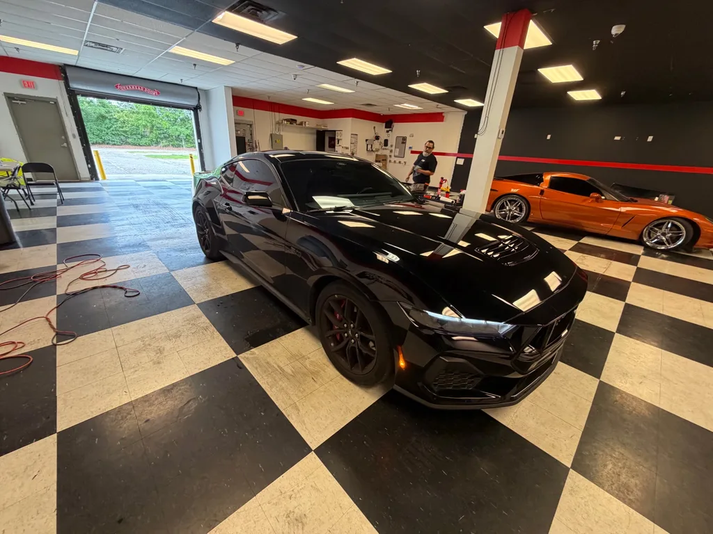 Black Ford Mustang and orange Corvette in the Pensacola install bay